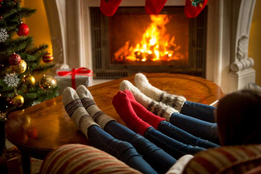 Feet of family in woolen socks warming at burning fireplace at living room on Christmas
